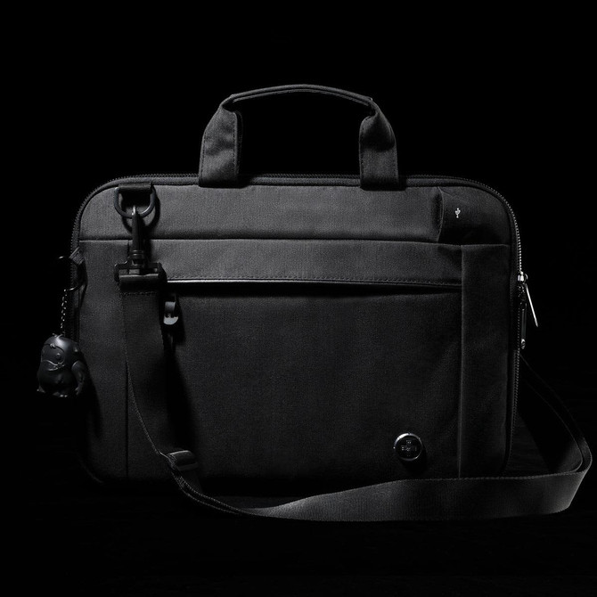 A black laptop sleeve with a handle and adjustable strap, featuring a front pocket and a small attached keychain.