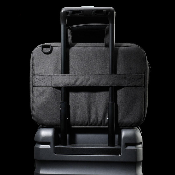 A black laptop sleeve with a handle, designed to fit securely on a suitcase's extendable handle.