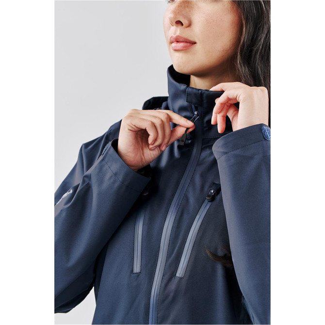 A woman adjusts the zip of a lightweight, navy rain jacket with a sleek design and a logo on the sleeve.
