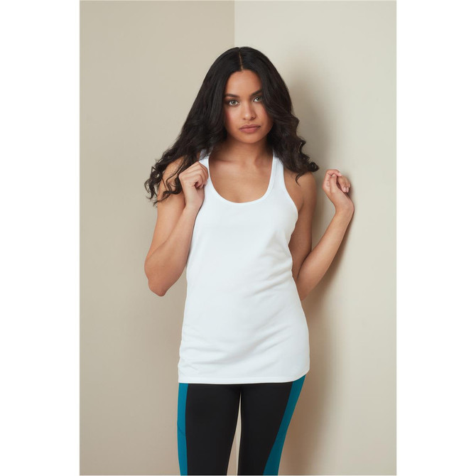 A woman models a white tank top, paired with black leggings featuring turquoise stripes. The top has a logo.
