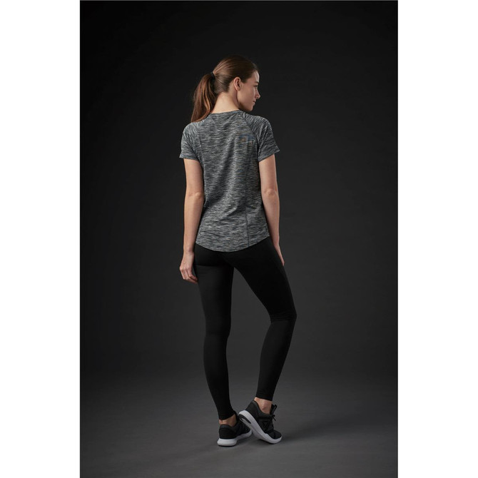 A woman is wearing a grey patterned short-sleeve T-shirt, paired with black leggings and sneakers. The back view is displayed.