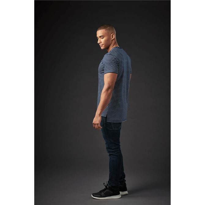 A man wearing a navy and white striped crew neck t-shirt, paired with dark jeans and black sneakers.