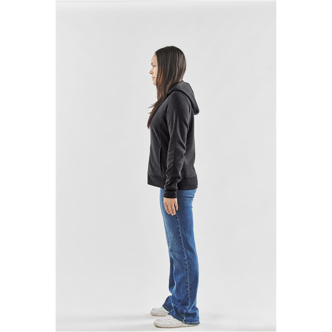 A woman stands sideways wearing a dark grey fleece full zip hoody, paired with blue jeans and white shoes.