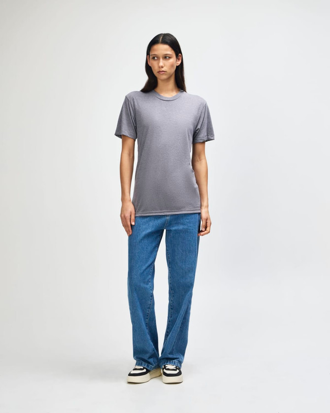 A model stands in a grey American Apparel tri-blend T-shirt and blue jeans, featuring a subtle logo.