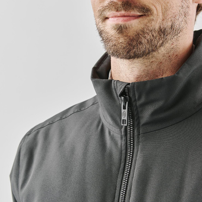 A grey thermal jacket featuring a high collar and zip closure, modelled by a man with a beard.
