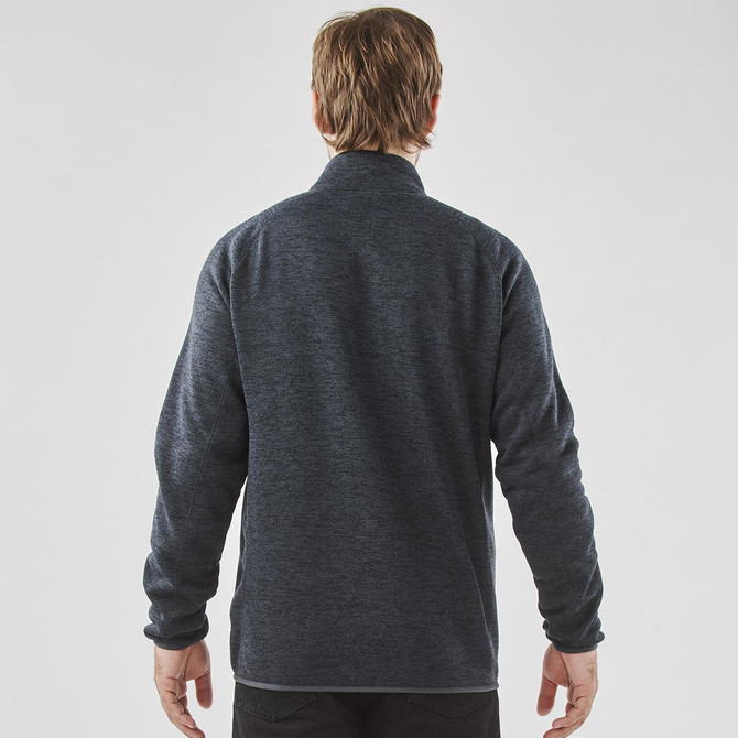 A men's full zip fleece jacket in dark grey, featuring a simple design and a collar. Branding is visible on the jacket.