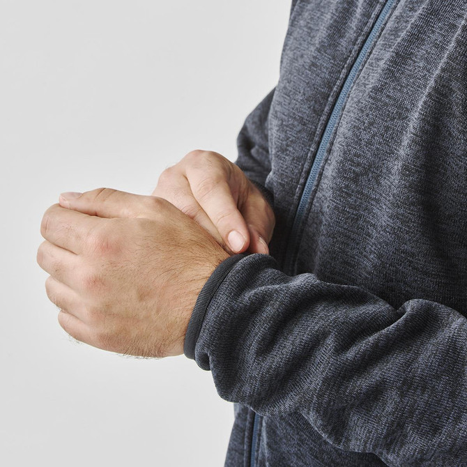 A men's fleece jacket in dark grey, featuring a full zip and fitted cuffs. The jacket has a logo on it.