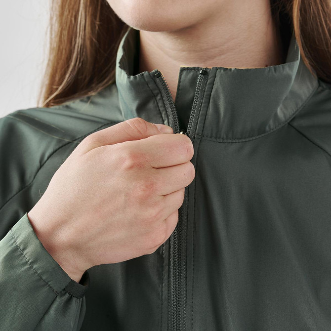A woman's hand zips up a green Pacifica full zip jacket, featuring a high collar and a subtle logo.
