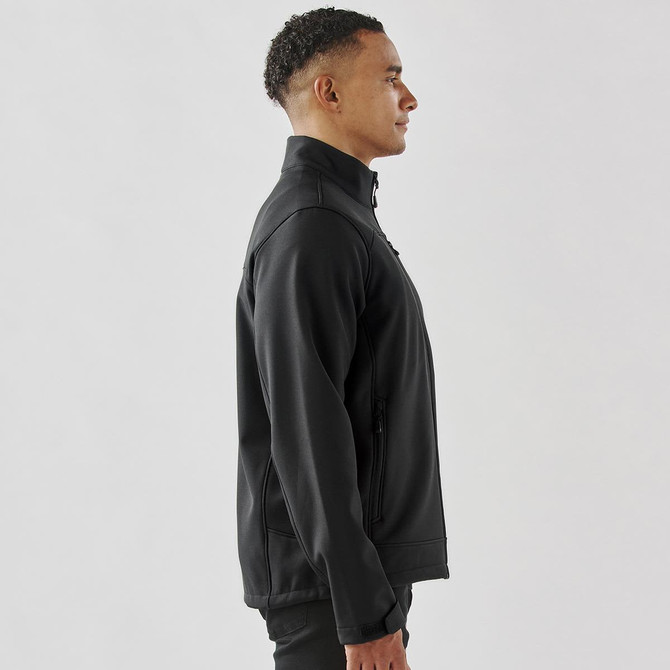 A side view of a men's black softshell jacket featuring a zip closure and pockets, with a logo on the chest.