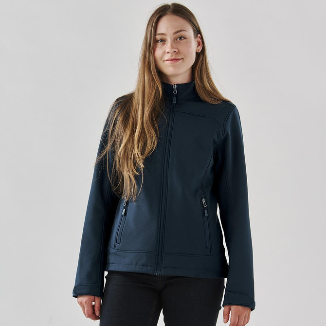A navy softshell jacket for women with a zippered front and two side pockets. It features a branding logo.