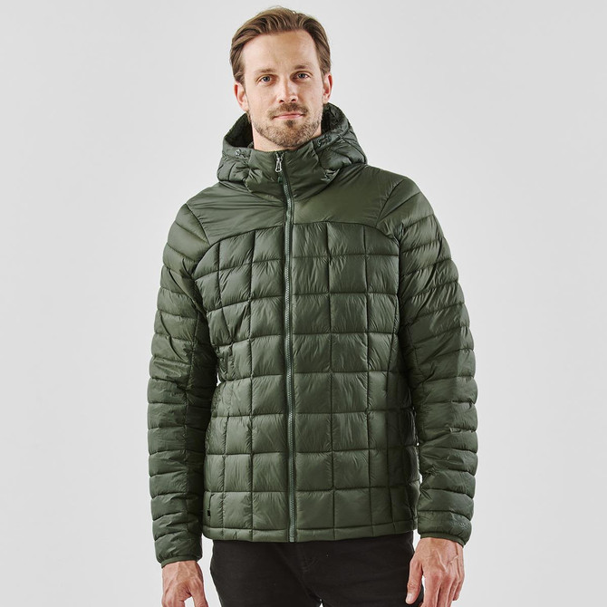 A man wearing a green puffer jacket with a hood, featuring a quilted design. The jacket has a logo on it.