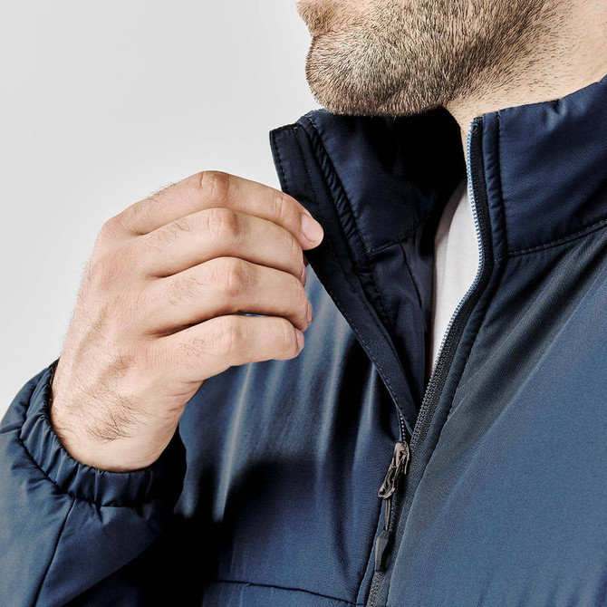 A close-up of a man wearing a navy blue Sierra Thermal Jacket, showcasing the collar and zipper detail.