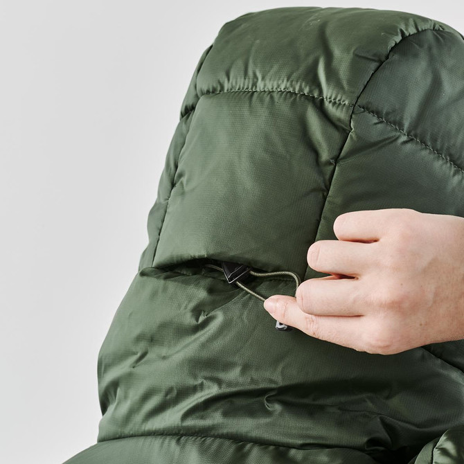 A close-up of a hand adjusting the hood of a green puffer jacket, featuring a logo on the back.
