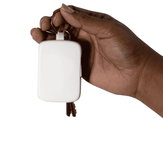 A hand holds a white rectangular keychain power bank, attached to metal keys.
