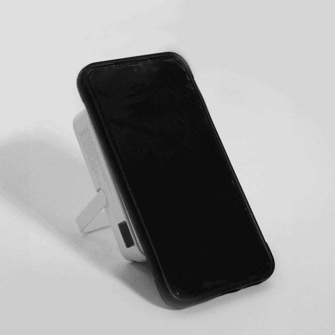 A wireless charging power bank in white, featuring a stand and a black face. It has a logo on the side.