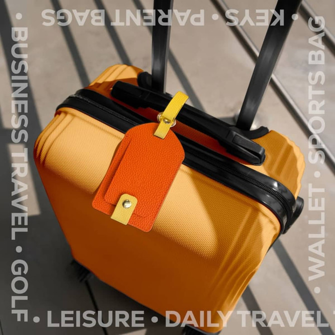 A bright yellow suitcase featuring an orange luggage tag attached, resting on a flat surface.