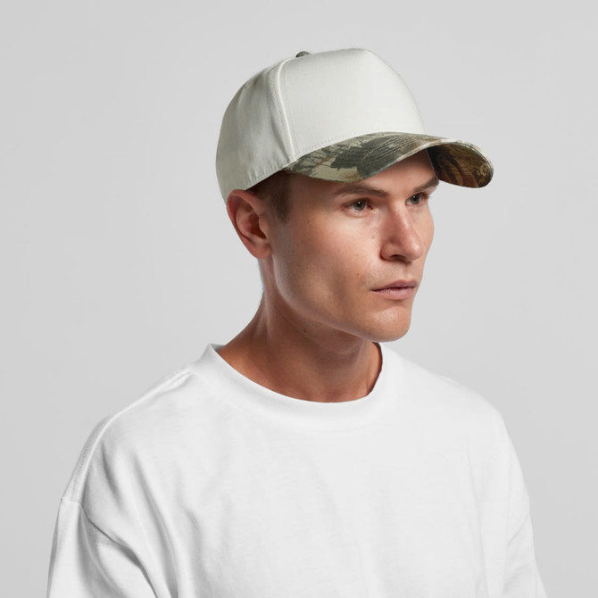 A two-tone camo cap featuring a light-coloured crown and a camouflage-patterned peak, displayed on a model.