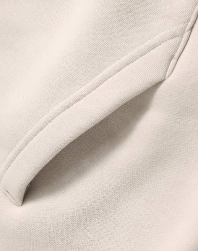 A close-up of a cream-coloured premium fleece oversized hoodie featuring a side seam pocket.