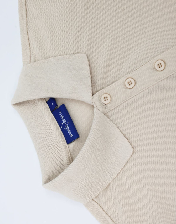 A beige ladies' classic cotton/poly pique short sleeve polo with a collar and buttons, featuring a branded label inside.