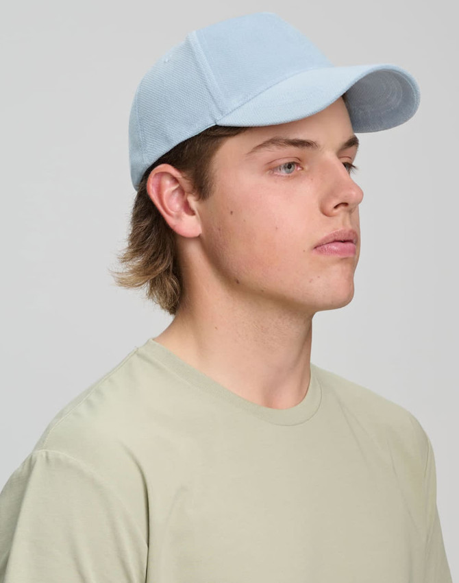 A light blue jacquard texture 5 panel cap worn by a young man with short hair and a beige t-shirt.