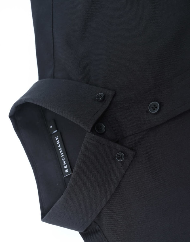 A black long-sleeved cotton blend shirt with a button-up collar and a logo on the inside label.