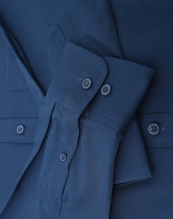 A navy blue long-sleeve cotton blend shirt with buttons and a folded sleeve detail. It features a logo.