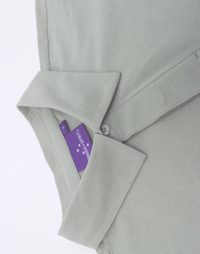 A light green men's polo shirt with a collar, showcasing a tag and button detail. It features branding on the tag.