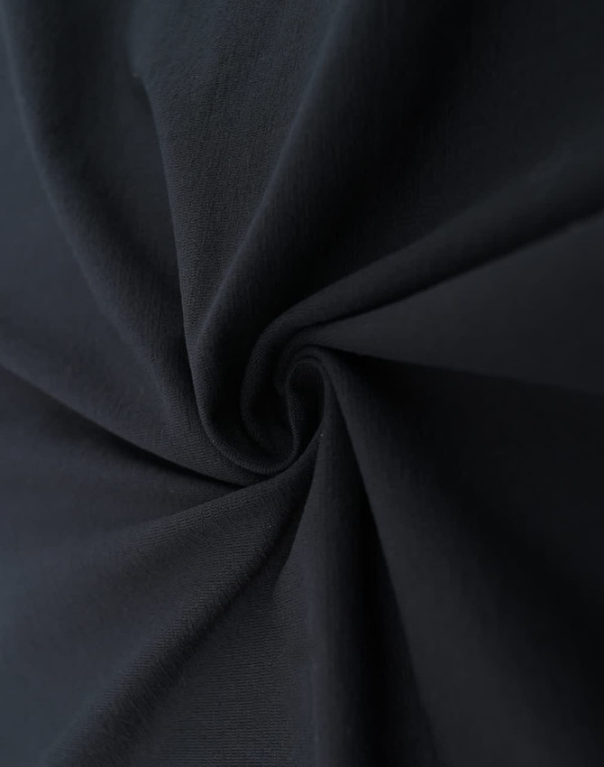A close-up of black fabric showcasing its smooth texture and flexibility. The material appears lightweight and breathable.