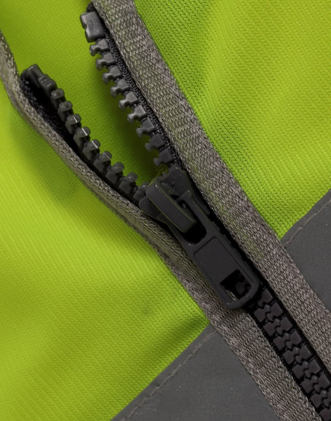 A close-up of a zip on a high visibility safety vest in bright yellow and grey. The vest features utility pockets.