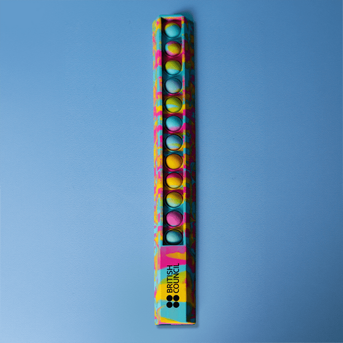 A 30cm popper ruler featuring a vibrant design with blue and multicoloured dots, alongside a logo.