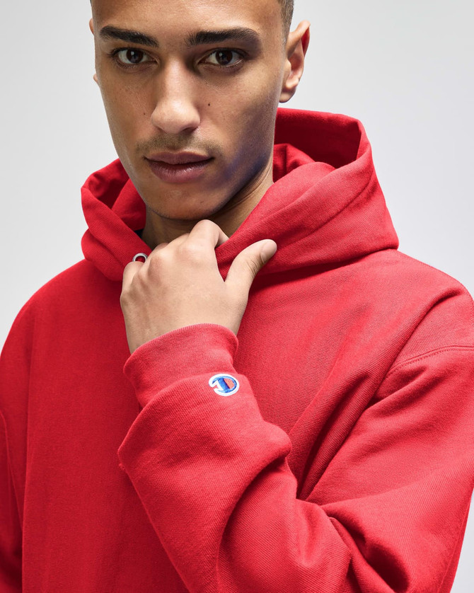 A red Champion Reverse Weave® adult pullover hooded sweatshirt with a logo on the sleeve.