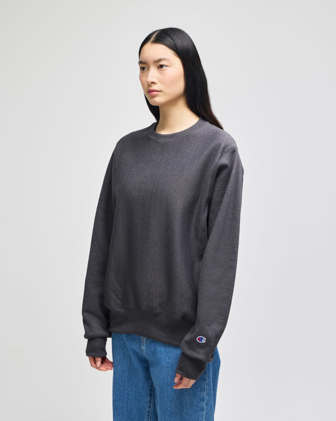A grey pullover hooded sweatshirt featuring long sleeves and a logo on the sleeve, worn by a model.