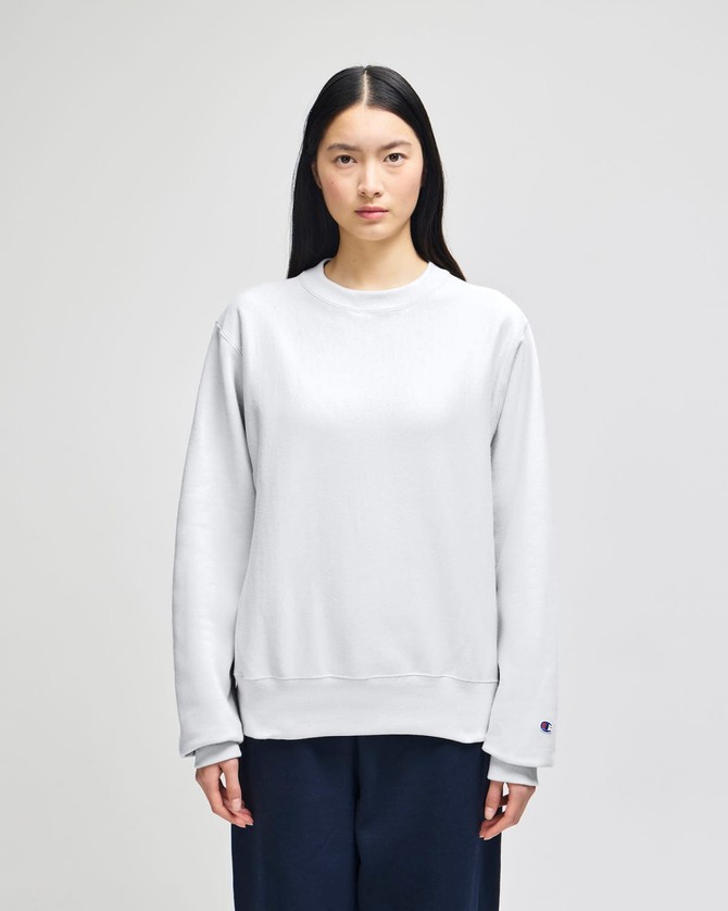 A grey Champion Reverse Weave® adult crew sweatshirt worn by a model, featuring a branding logo.