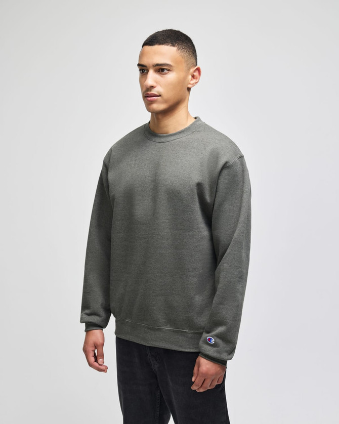 A green adult crewneck sweatshirt with a logo patch, featured on a model.