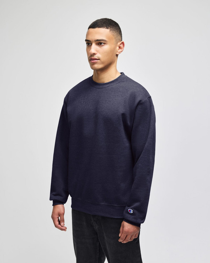 A dark navy crewneck sweatshirt on a model, featuring a logo on the sleeve and a relaxed fit.