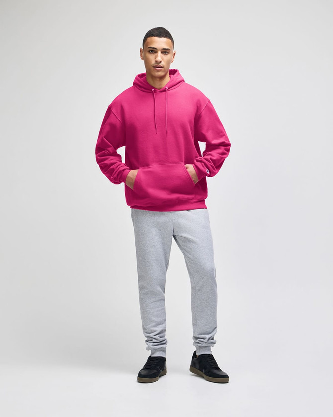 A pink pullover hooded sweatshirt with a front pocket, paired with grey sweatpants and black shoes.