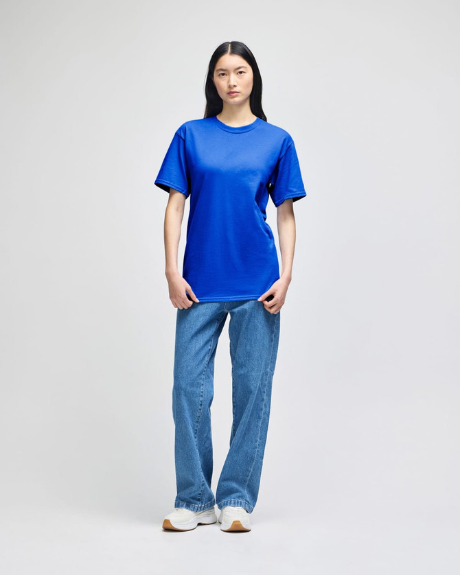 A blue Champion adult short-sleeve t-shirt displayed on a model, paired with light blue jeans and white shoes.