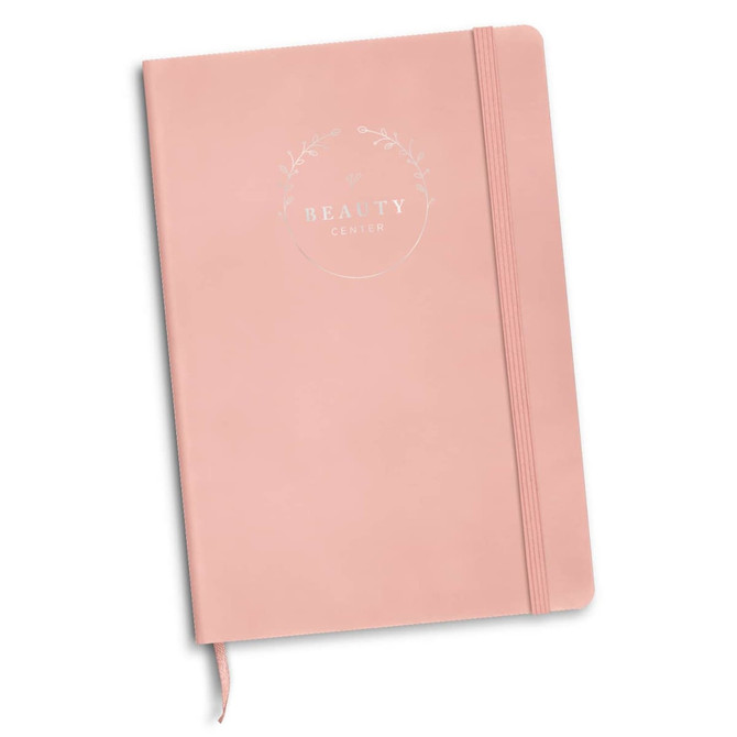 A pink notebook with a foil-printed design and an elastic band closure. It features a branding logo on the cover.