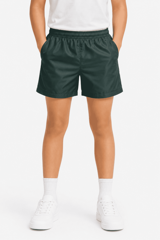 Kids' sports shorts in dark green with an elastic waistband and side pockets, paired with white shoes and socks.