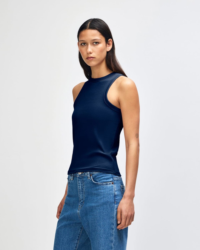 A fitted navy tank top with a sleeveless design, paired with blue jeans. The product features a subtle logo.