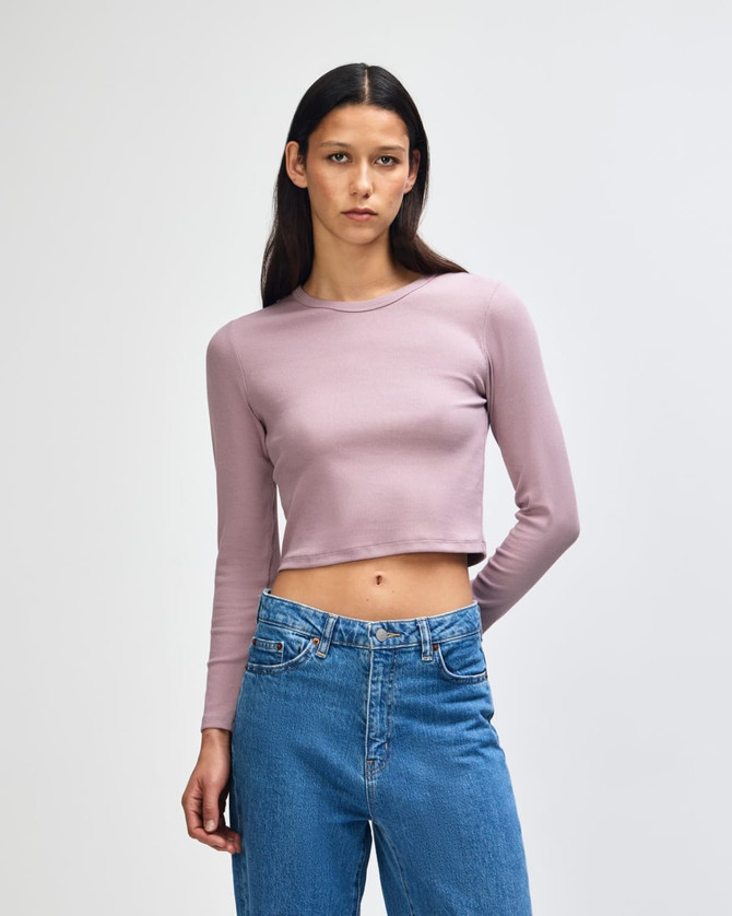 A fitted long-sleeve crop t-shirt in a soft mauve colour, paired with high-waisted blue jeans.