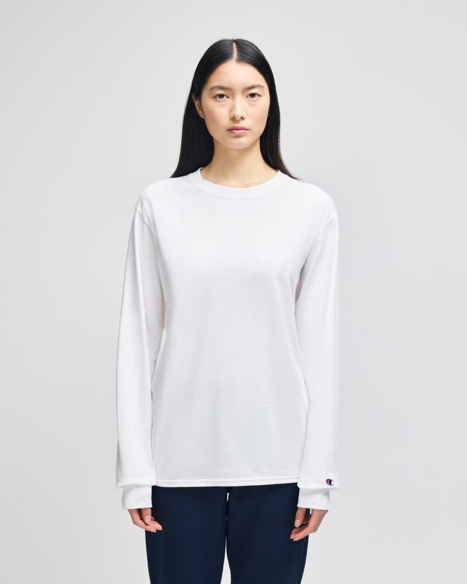 A long-sleeve white T-shirt for adults featuring a logo, modelled by a person with long hair.