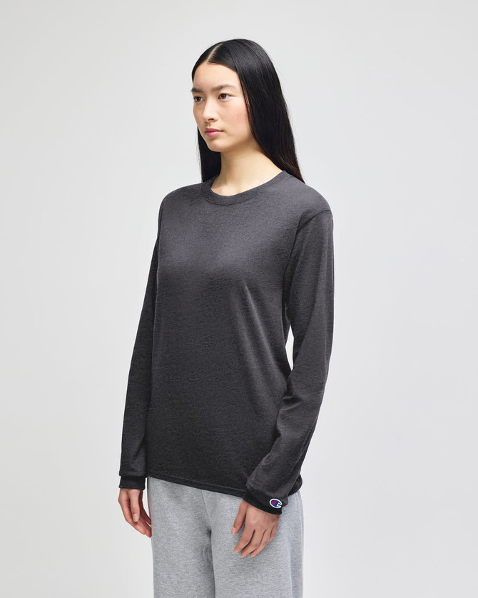 A long-sleeve t-shirt in dark grey, featuring a logo, displayed on a model with straight black hair.