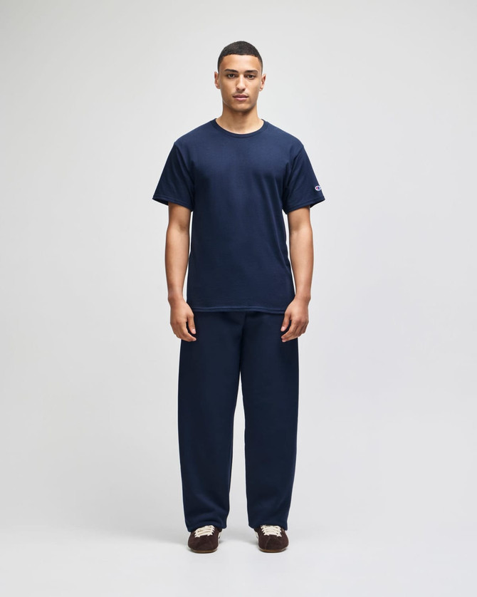 A navy blue short sleeve t-shirt displayed on a model, paired with matching navy pants, featuring a logo on the shirt.