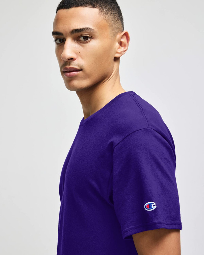 A purple Champion Adult Jersey Short Sleeve T-Shirt worn by a model, featuring a small logo on the sleeve.