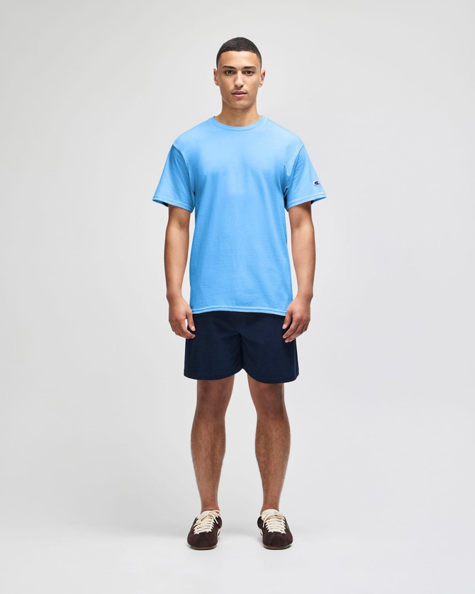 A light blue Champion adult jersey short sleeve t-shirt, worn by a man with navy shorts and brown shoes.