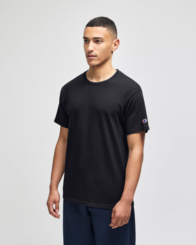 A black short sleeve t-shirt with a logo on the sleeve, displayed by a model standing against a neutral background.