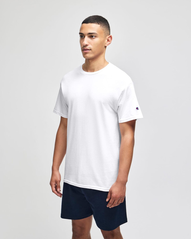 A white short sleeve t-shirt displayed on a model, featuring a logo on the sleeve, paired with navy shorts.
