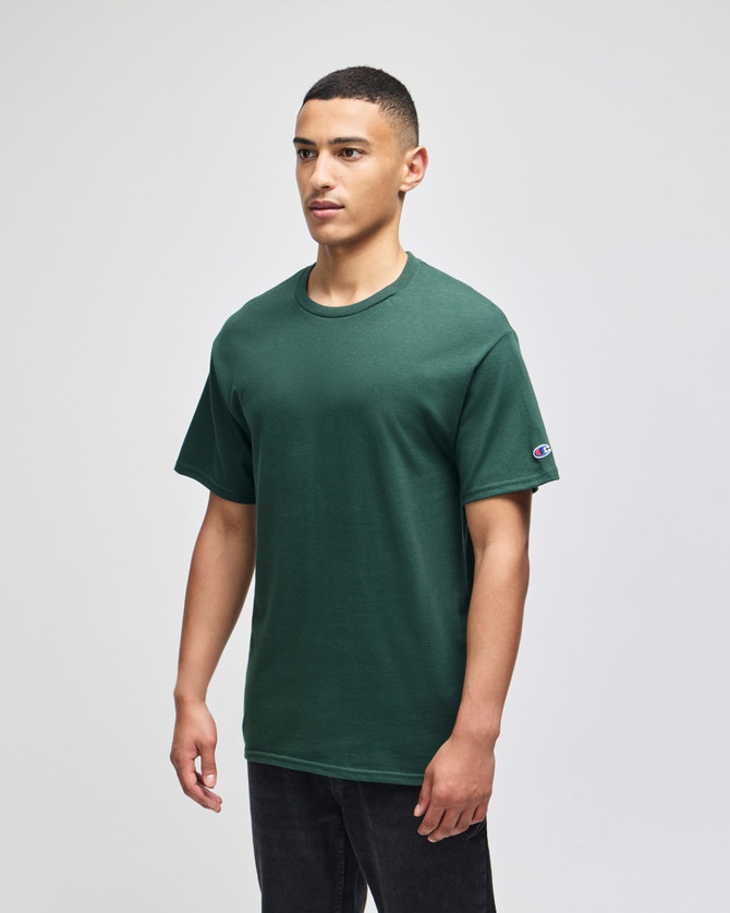 A green Champion Adult Jersey Short Sleeve T-Shirt displayed on a model, featuring a small logo on the sleeve.