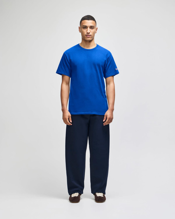 A blue short sleeve jersey t-shirt worn with navy pants, featuring a logo on the sleeve.